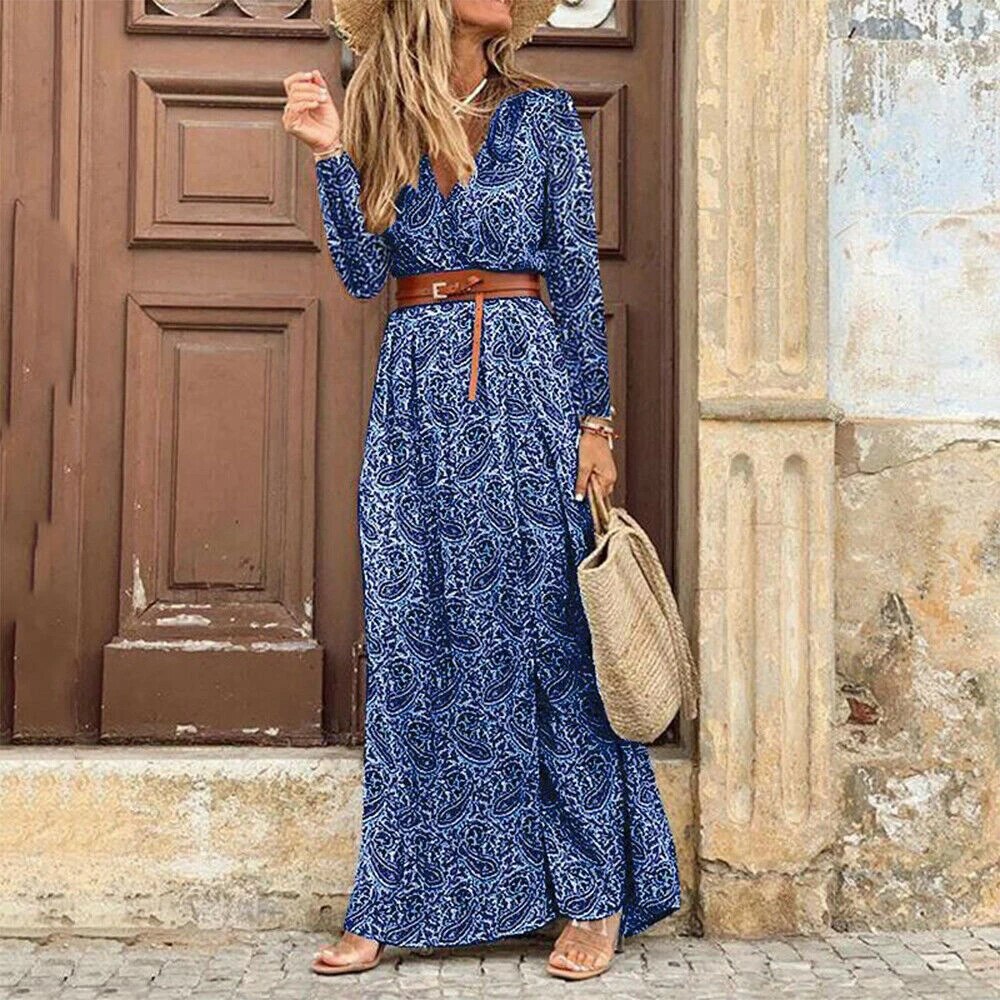 Femme en robe longue bleue à motifs, ceinture marron, chapeau de paille, sac en osier, devant porte en bois. Mode estivale élégante.