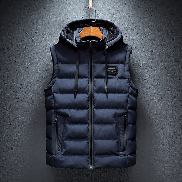 Gilet sans manches matelassé bleu marine avec capuche, fermeture éclair, poches zippées, suspendu sur un cintre. Mode hiver homme.