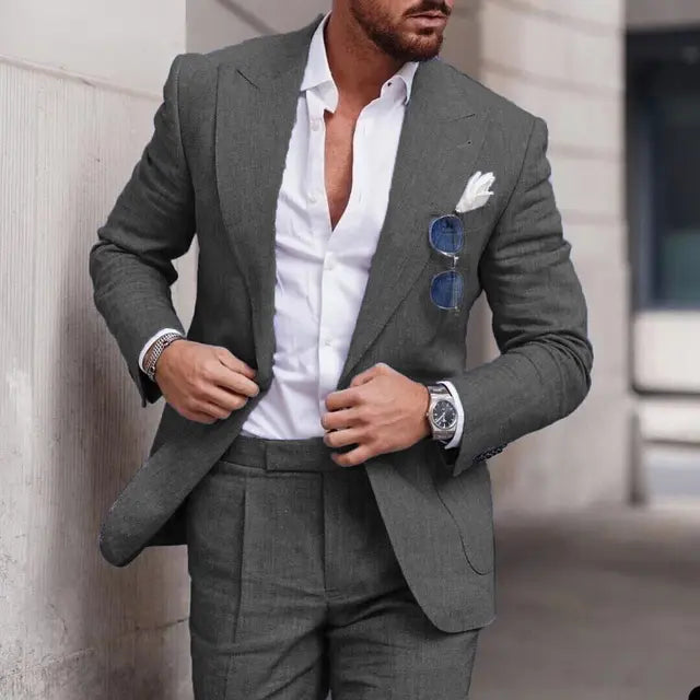 Homme en costume gris élégant, chemise blanche, lunettes de soleil bleues, montre argentée, style mode masculine chic, urbain et sophistiqué.