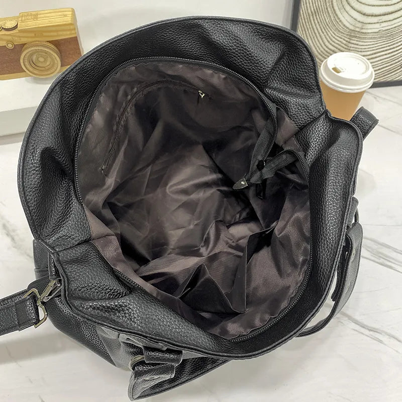 Sac à main en cuir noir ouvert sur une table en marbre, montrant l'intérieur vide. À côté, un gobelet de café en carton. Accessoire mode élégant.