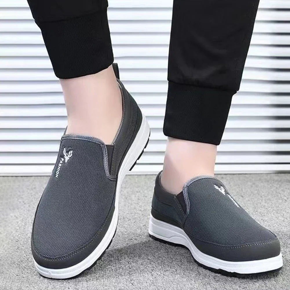 Chaussures slip-on grises pour homme, semelle blanche, design moderne et confortable, idéales pour la marche et le quotidien.