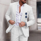 Homme en costume blanc élégant, chemise ouverte, lunettes de soleil accrochées, montre-bracelet argentée, style mode masculine chic et moderne.