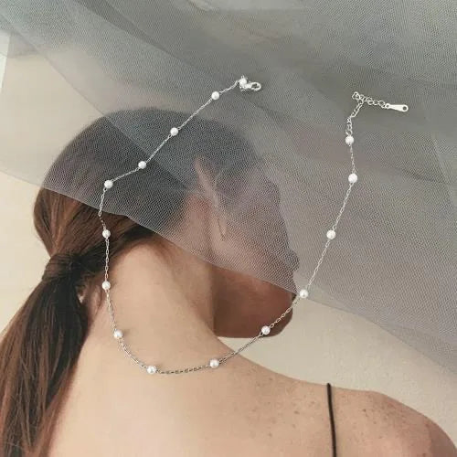 Collier en argent avec perles sur fond de femme voilée, bijou élégant et moderne, accessoire de mode tendance, style minimaliste.