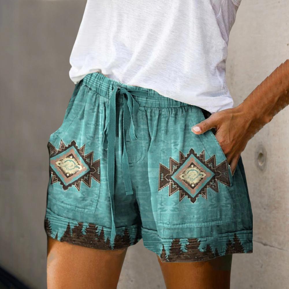 Short en lin vert avec motifs ethniques géométriques, poches latérales, et cordon de serrage, porté par une personne en t-shirt blanc.
