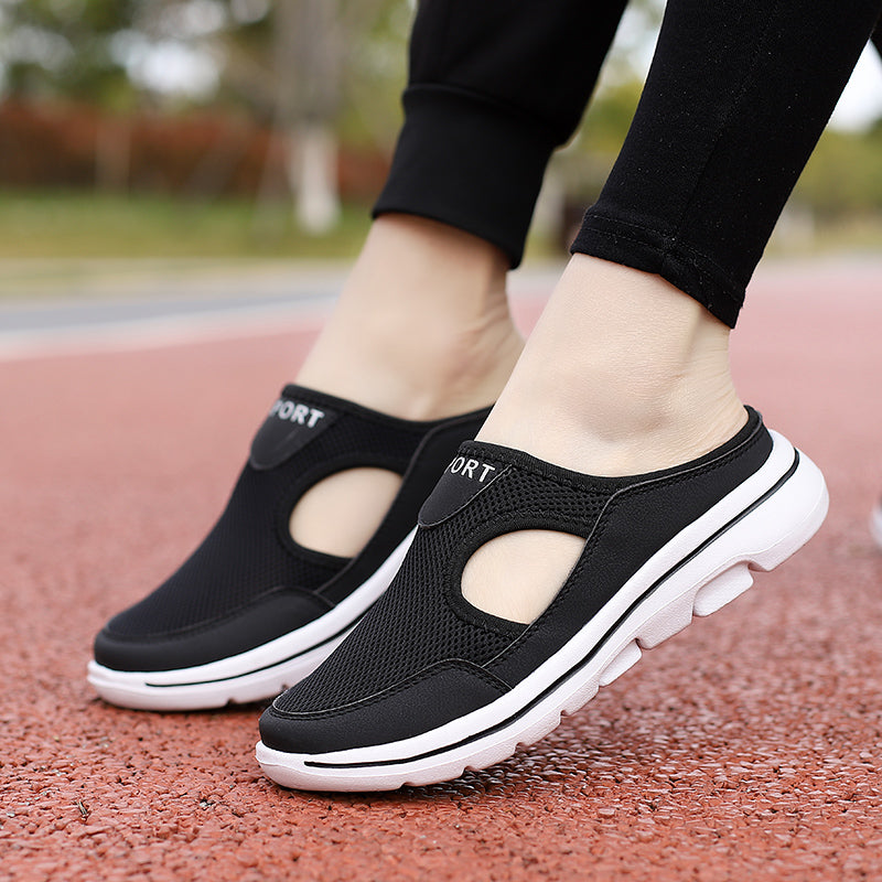 Chaussures de sport noires pour femmes avec semelles blanches, design respirant et ouvert, portées sur une piste de course rouge.
