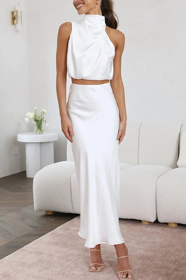 Femme portant une élégante robe blanche sans manches, jupe longue, debout dans un salon moderne. Mode chic, tenue de soirée, style minimaliste.