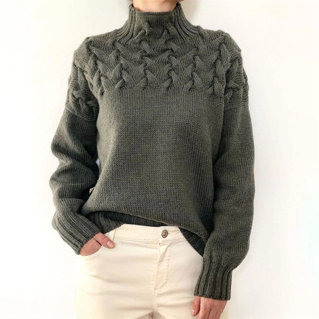 Pull en laine gris avec motif torsadé, col montant, manches longues, porté par une personne. Mode hiver, style décontracté, tendance tricot.