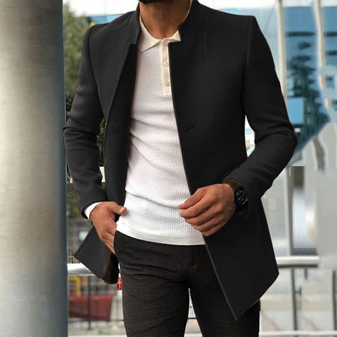 Homme en manteau noir élégant, chemise blanche, montre noire, style urbain moderne, mode masculine, tenue chic, extérieur urbain.