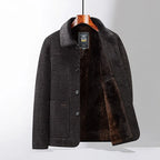 Veste en laine grise pour homme avec doublure en fourrure marron, suspendue sur un cintre en bois. Mode masculine élégante, hiver, chaud.