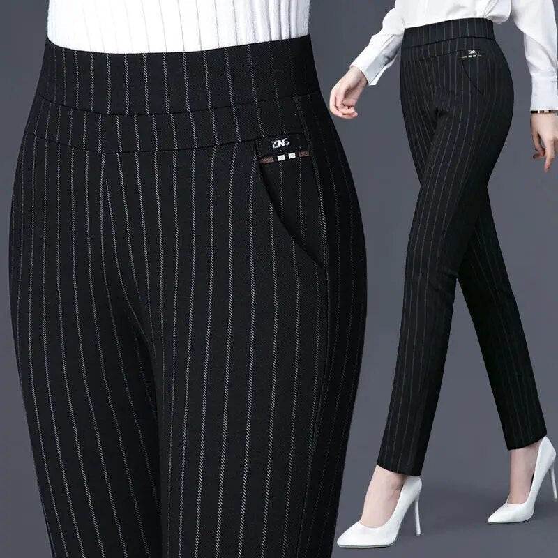Pantalon femme noir à rayures blanches, taille haute, coupe ajustée, poches latérales, porté avec des talons blancs. Mode élégante et professionnelle.