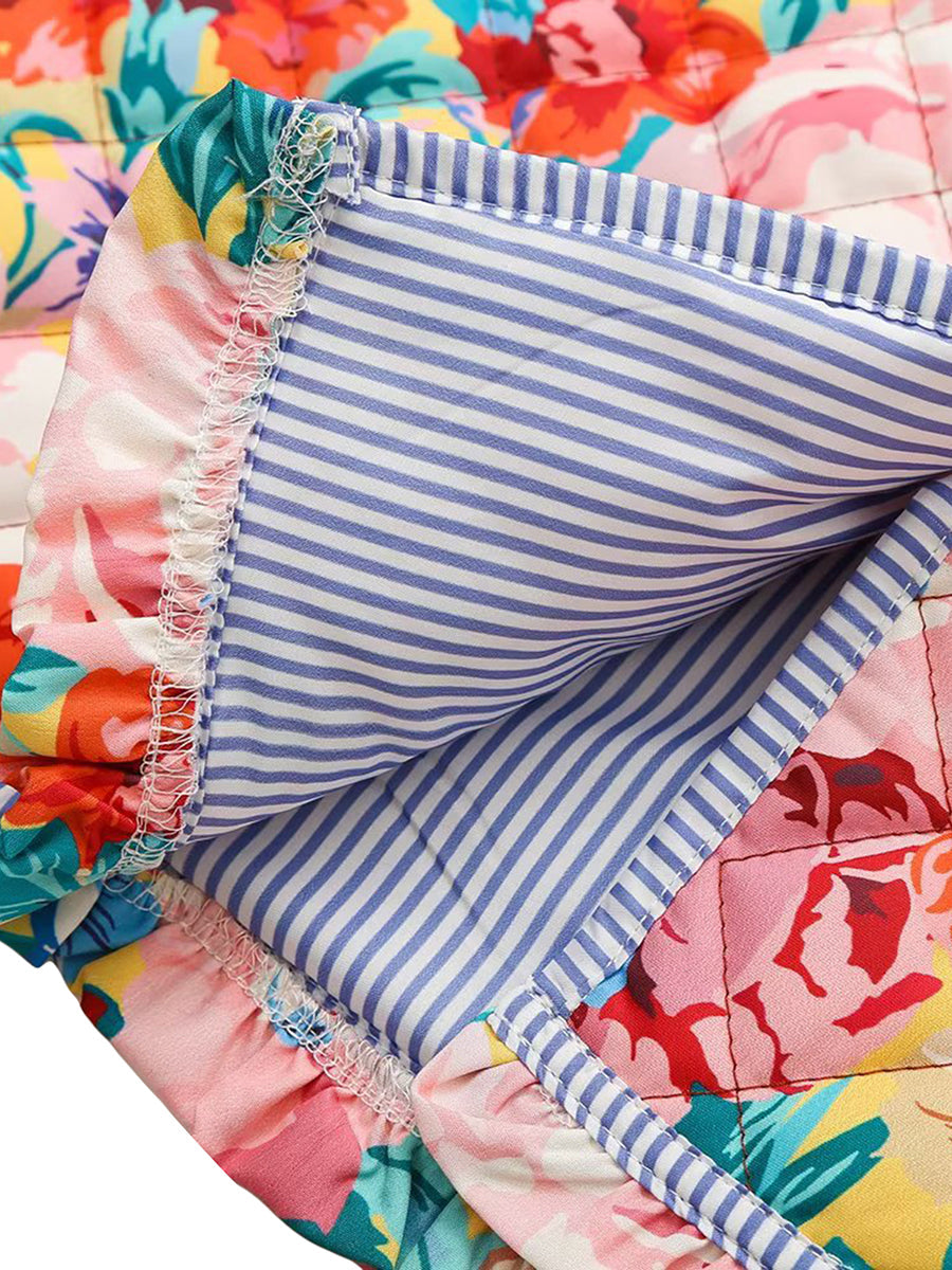 Couverture matelassée à motifs floraux colorés avec doublure rayée bleue et blanche, couture détaillée. Accessoire déco maison tendance.