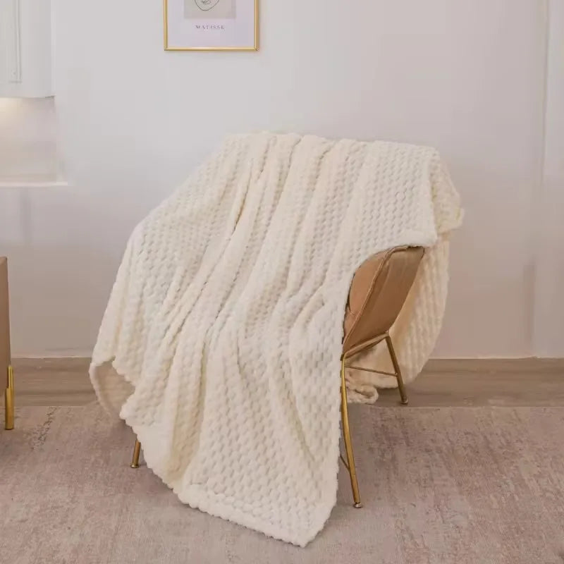 Plaid en laine blanche texturée drapé sur un fauteuil moderne en métal doré, intérieur minimaliste, décoration cosy et élégante.