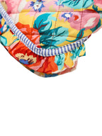 Coussin floral coloré avec motifs floraux vifs, bordure rayée bleue et blanche, design vibrant et moderne, décoration intérieure tendance.