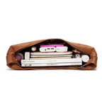 Sac à main en cuir marron ouvert, contenant magazines, chargeur portable, rouge à lèvres, et accessoires divers. Organisation élégante et pratique.