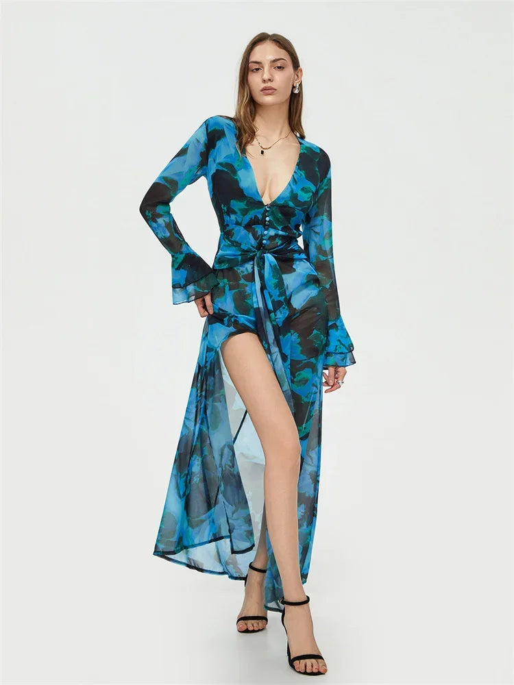 Robe longue bleue à motifs floraux, manches longues, décolleté en V, fendue, portée par une femme. Mode élégante, tendance, soirée.