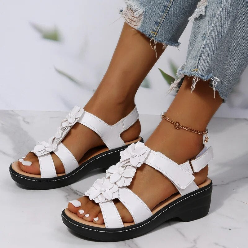 Sandales blanches à talons compensés avec fleurs, portées avec un jean déchiré. Chaussures d'été élégantes pour femmes, mode tendance.