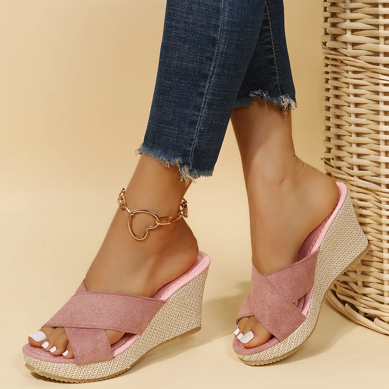 Sandales compensées roses en daim avec semelle en corde, portées avec un jean skinny déchiré. Chaussures d'été tendance pour femmes.