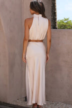 Robe longue dos nu beige élégante, femme de dos, style chic et moderne, tenue estivale, mode féminine tendance, extérieur ensoleillé.