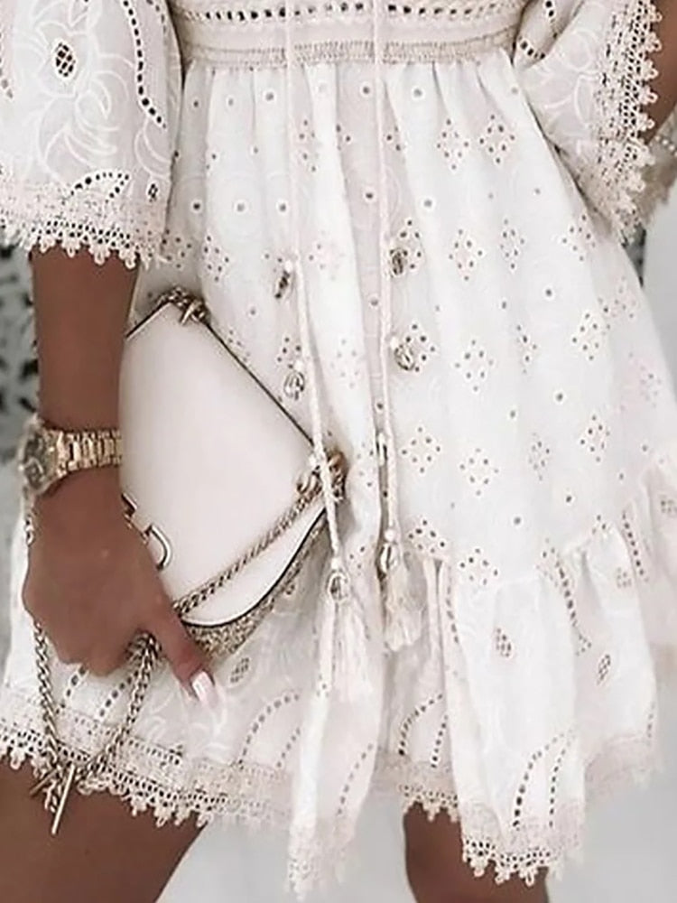 Robe blanche en dentelle brodée avec sac à main beige, tenue élégante et estivale, mode féminine chic, détails délicats et accessoires assortis.