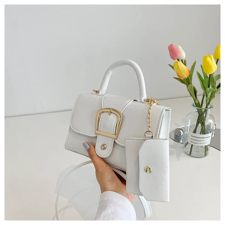 Sac à main blanc élégant avec boucle dorée, porté à la main. Vase avec tulipes colorées en arrière-plan. Accessoire mode chic et tendance.