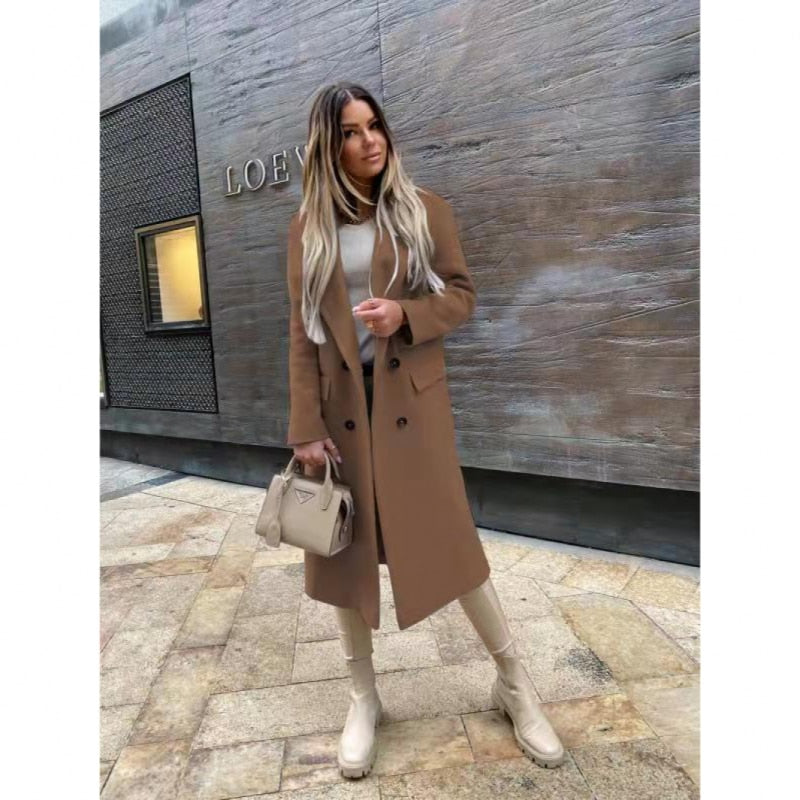 Femme portant un manteau marron, bottes beiges et sac à main beige devant un mur texturé. Mode automne-hiver, style urbain chic.