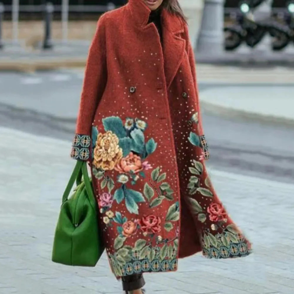 Manteau rouge en laine avec motifs floraux colorés, porté par une femme, sac vert vif à la main. Mode automne-hiver, style élégant et tendance.