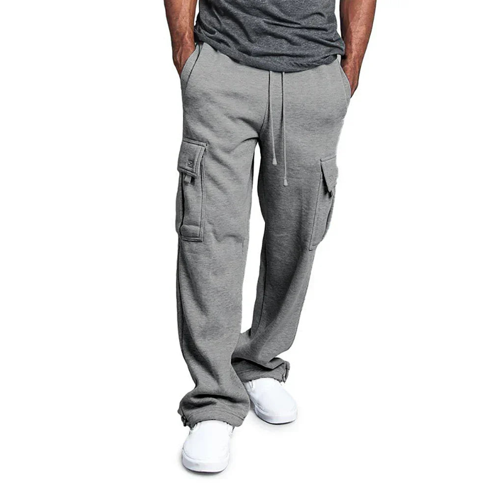 Pantalon cargo gris pour homme, style décontracté, poches latérales, cordon de serrage, porté avec t-shirt gris et baskets blanches.