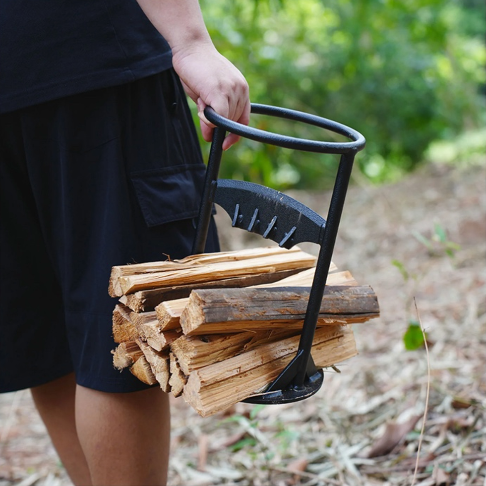 Homme portant du bois de chauffage avec un porte-bûches en métal noir dans une forêt. Accessoire pratique pour transporter du bois.
