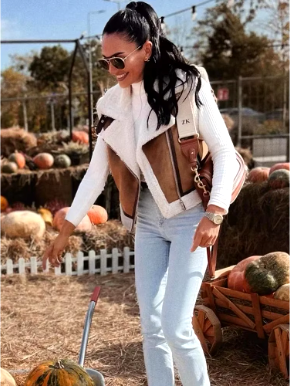 Femme souriante en veste en cuir et lunettes de soleil, debout dans une ferme de citrouilles, tenant une pelle. Automne, récolte, mode décontractée.