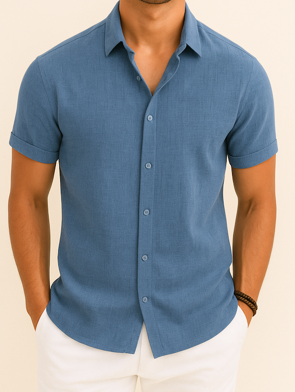 Homme portant une chemise bleue à manches courtes, élégante et décontractée, avec un bracelet marron, sur fond beige. Mode masculine estivale.