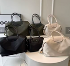 Six sacs à main élégants en toile, couleurs noir, kaki et beige, exposés sur une table blanche. Accessoires mode tendance pour femmes.