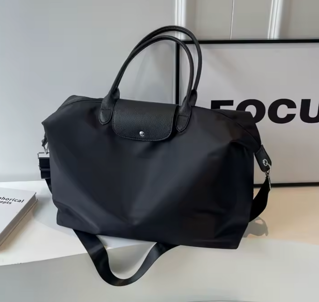 Sac à main noir élégant en cuir et nylon, posé sur une étagère blanche. Design moderne, idéal pour la mode féminine et les accessoires de luxe.