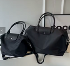 Deux sacs à main noirs élégants avec poignées en cuir, posés sur une étagère blanche. Design moderne et chic, parfait pour la mode urbaine.
