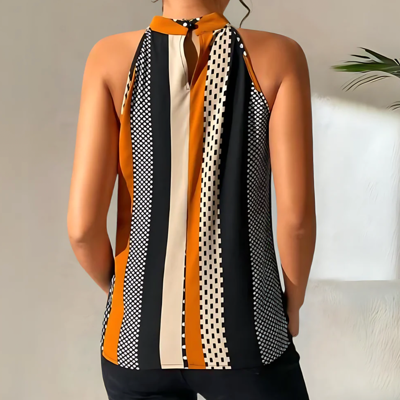Haut sans manches à rayures noires, blanches et orange, motif géométrique, femme de dos, style moderne, mode féminine élégante.