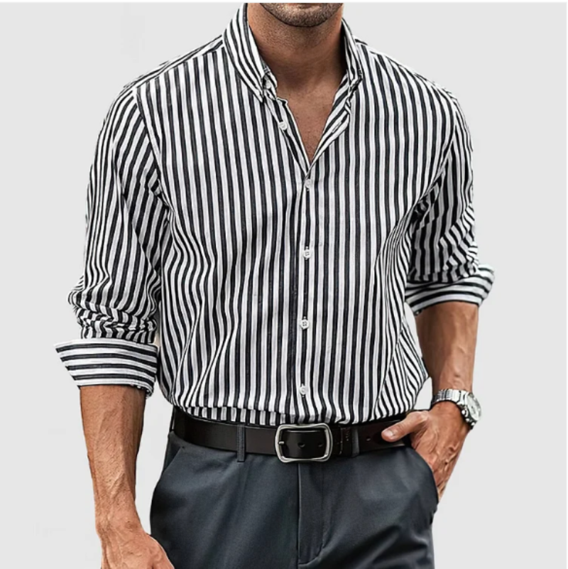 Chemise à rayures noires et blanches pour homme, manches longues retroussées, portée avec un pantalon gris et une ceinture noire. Style élégant et moderne.