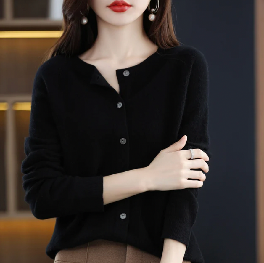 Femme portant un cardigan noir élégant, manches longues, boutons visibles, accessoires minimalistes, ambiance chic et moderne.