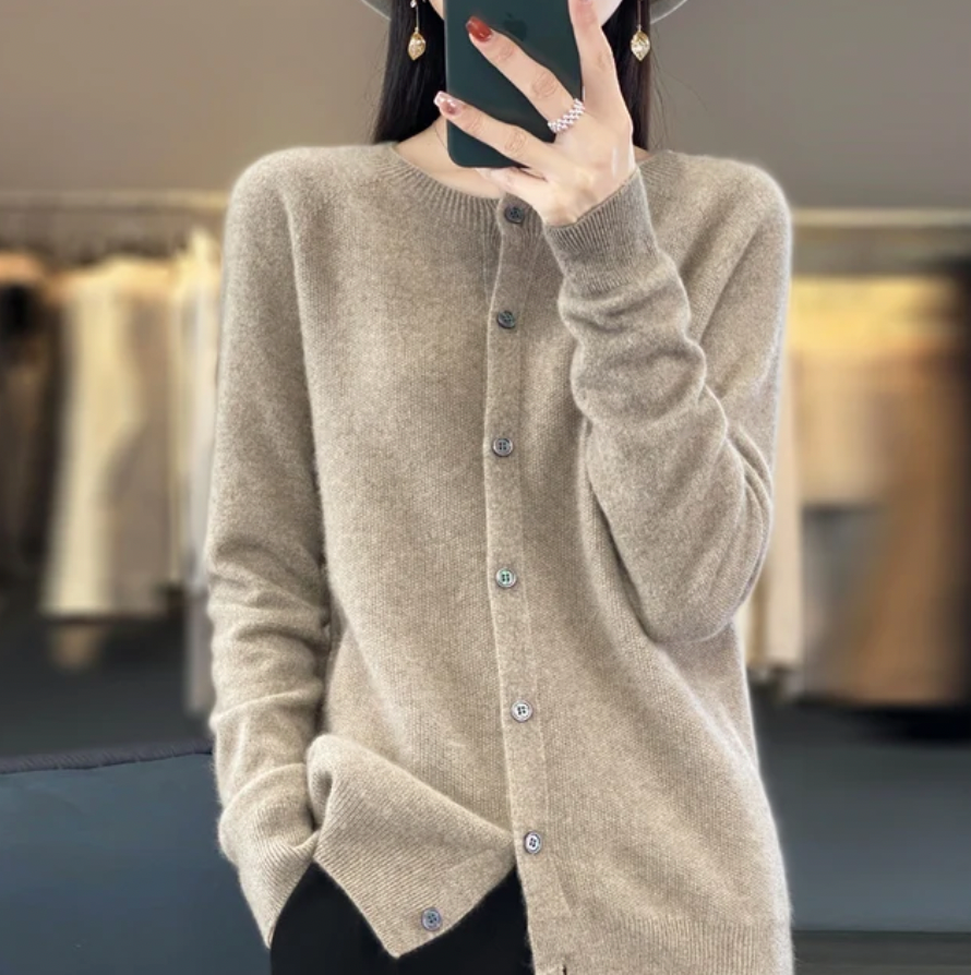 Femme portant un cardigan beige en cachemire, boutons en nacre, dans une boutique de mode. Style élégant et confortable, tendance automne-hiver.
