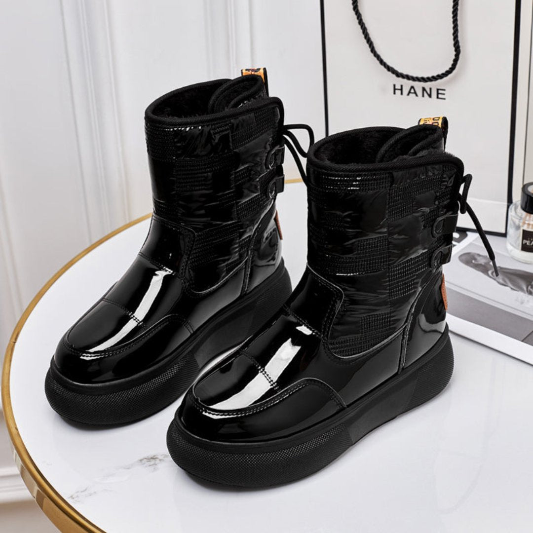 Bottes noires en cuir verni sur une table ronde blanche, design moderne et élégant, idéales pour l'hiver. Accessoire de mode tendance et chic.