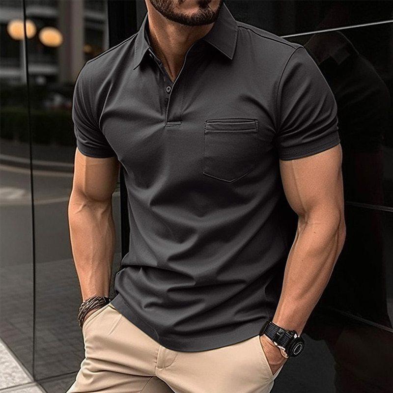 Homme portant un polo gris ajusté, manches courtes, avec une poche poitrine, montre noire, bracelet en cuir, pantalon beige, en extérieur urbain.