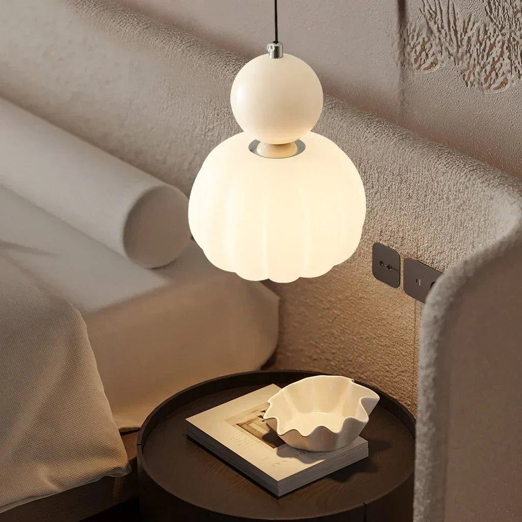 Lampe suspendue moderne en forme de globe au-dessus d'une table de chevet avec livre et plat décoratif, éclairage intérieur élégant.