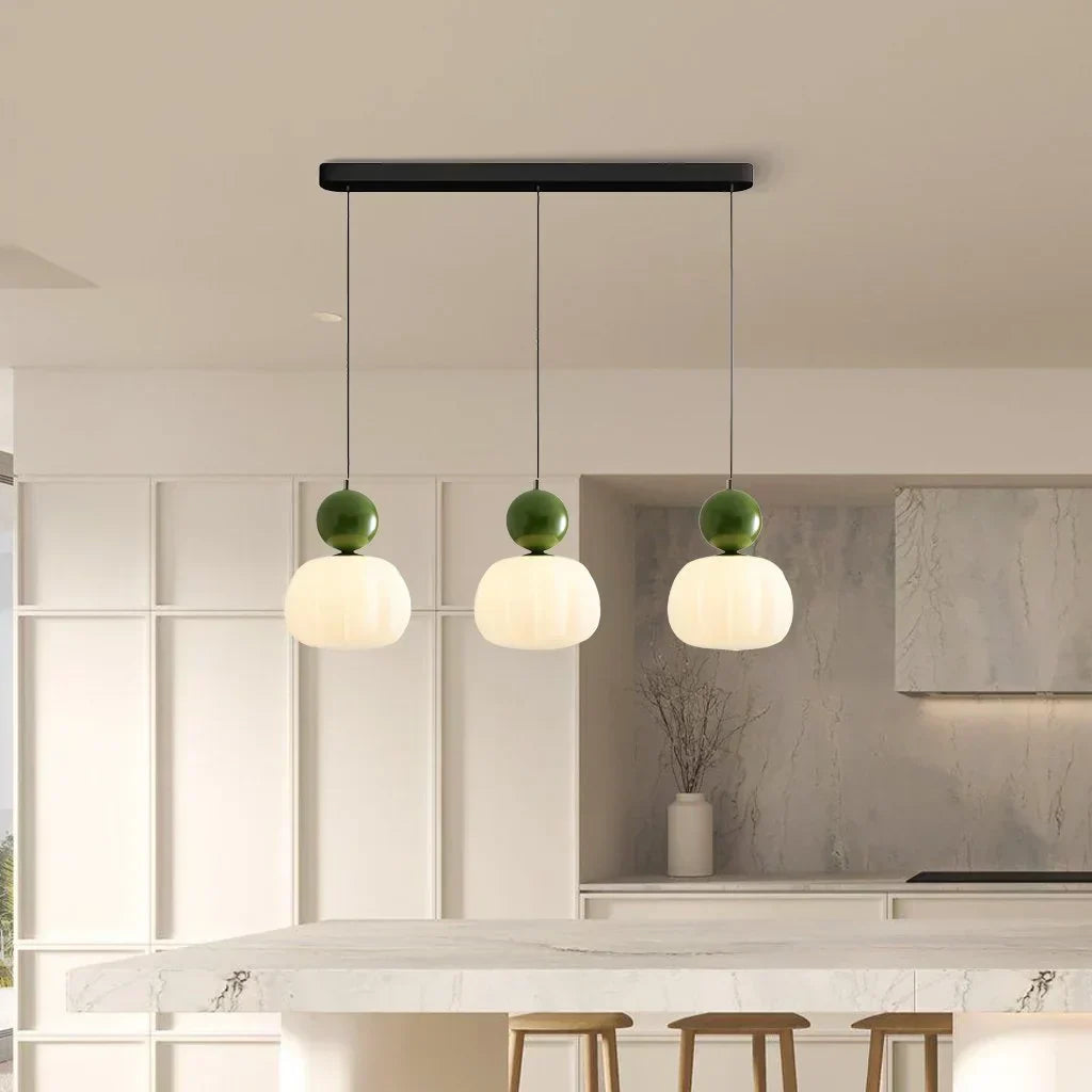 Suspension moderne à trois abat-jours blancs et sphères vertes, cuisine contemporaine, éclairage intérieur design, décoration minimaliste.