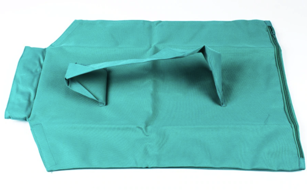 Sac en tissu vert réutilisable, plié avec poignées, sur fond blanc. Accessoire écologique pour courses, mode de vie durable.