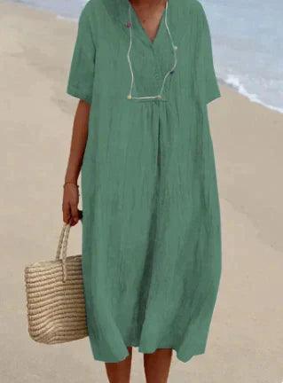 Robe verte ample en lin sur plage, tenue d'été décontractée, sac en osier à la main, mode féminine estivale, style plage chic.