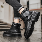 Bottes noires en cuir pour homme, semelles épaisses antidérapantes, style urbain, mode automne-hiver, sur fond de rue pavée.