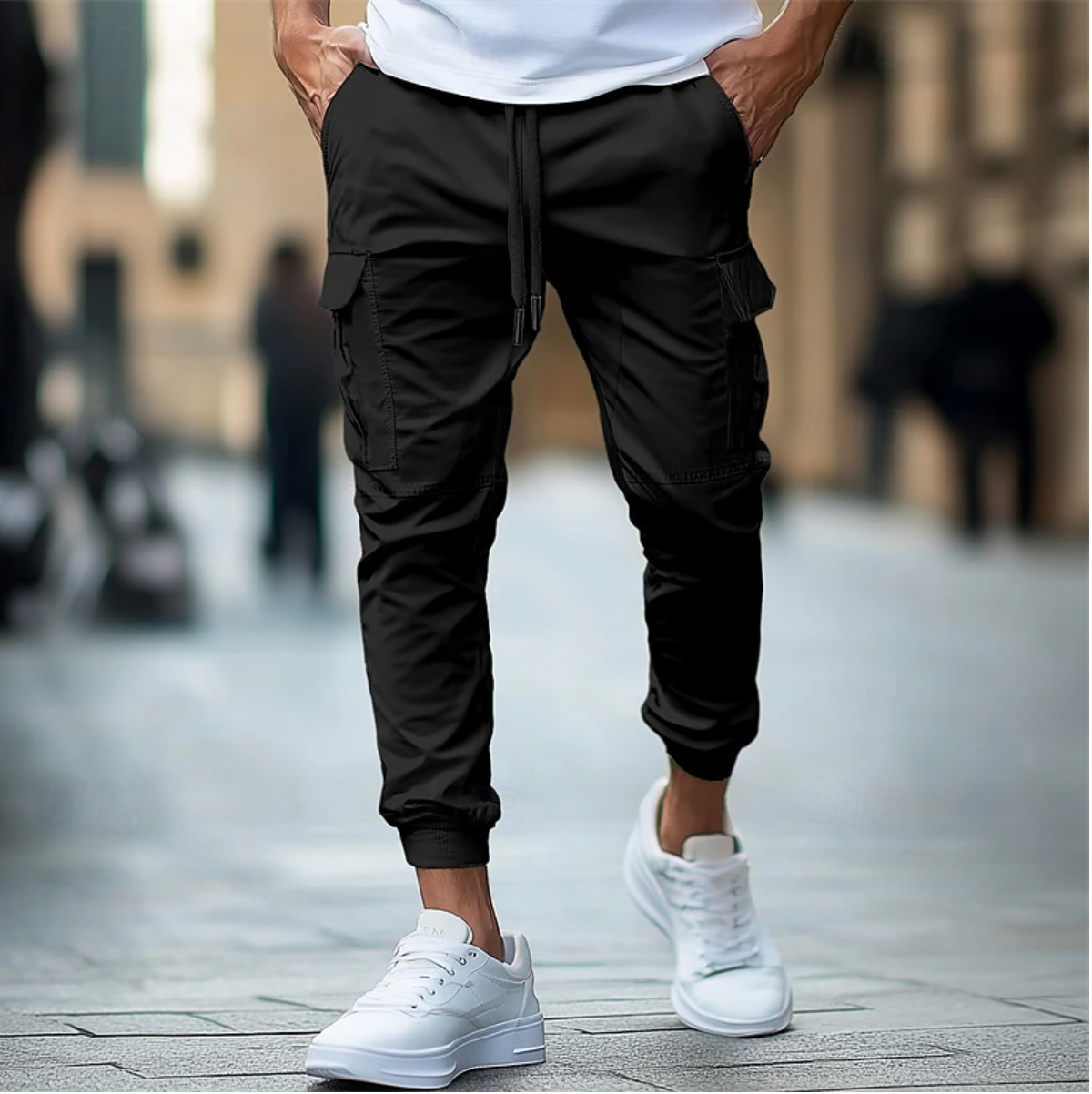 Homme portant un pantalon cargo noir et des baskets blanches, marchant en ville. Mode urbaine, style décontracté, tendance masculine.