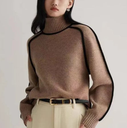 Femme portant un pull en laine marron à col roulé, manches longues, bordures noires, ceinture noire, pantalon beige. Mode automne-hiver élégante.