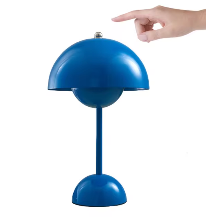 Lampe de table design bleu vif avec abat-jour hémisphérique, main pointant vers le haut. Éclairage moderne, décoration intérieure élégante.