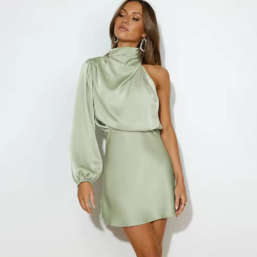 Robe satinée vert clair à une manche, femme posant élégamment, mode tendance, tenue de soirée chic, accessoires minimalistes, fond blanc.