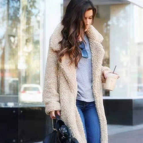 Jeune femme en manteau en fausse fourrure beige, tenant un café glacé et un sac noir, marchant en ville. Mode automne, style décontracté.