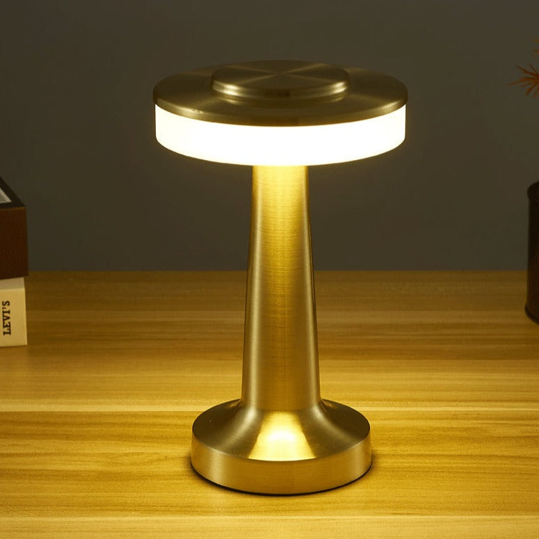 Lampe de table LED dorée moderne sur bureau en bois, éclairage d'ambiance élégant, design minimaliste, idéale pour décoration intérieure contemporaine.